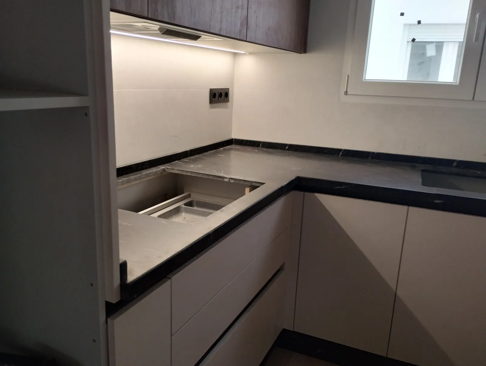 Tira LED bajo los muebles altos de una cocina, iluminando la encimera